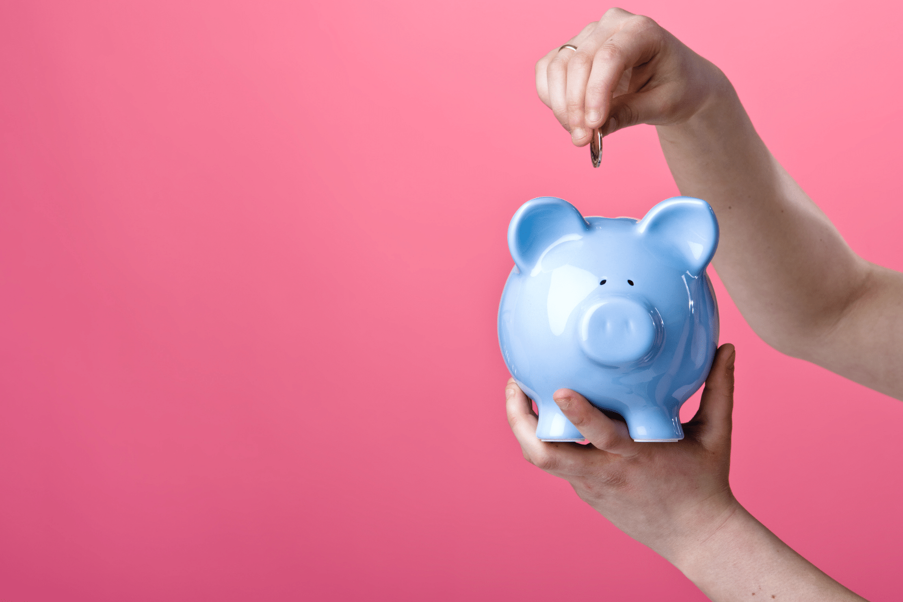 photo of a hand putting a coin into a blue piggybank